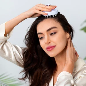 «خانمی در حال ماساژ پوست سر با ابزار مخصوص مراقبت مو؛ نمایی مرتبط با روتین زیبایی و تأثیر هیالورونیک اسید بر سلامت پوست، مو و ناخن»